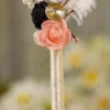 Detailed shot of the black and peach foam roses, gold rhinestone button, and bead sprigs