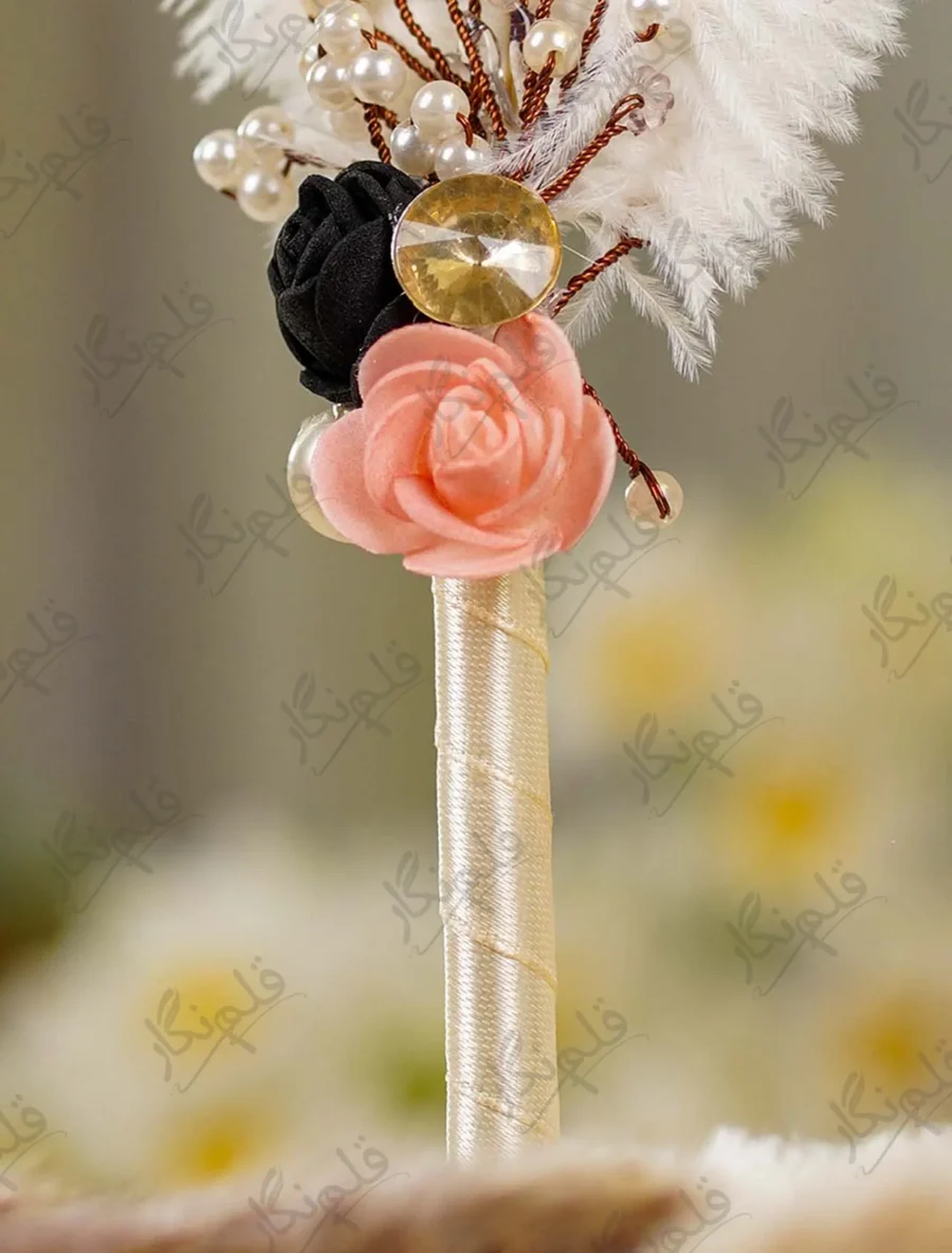 Detailed shot of the black and peach foam roses, gold rhinestone button, and bead sprigs