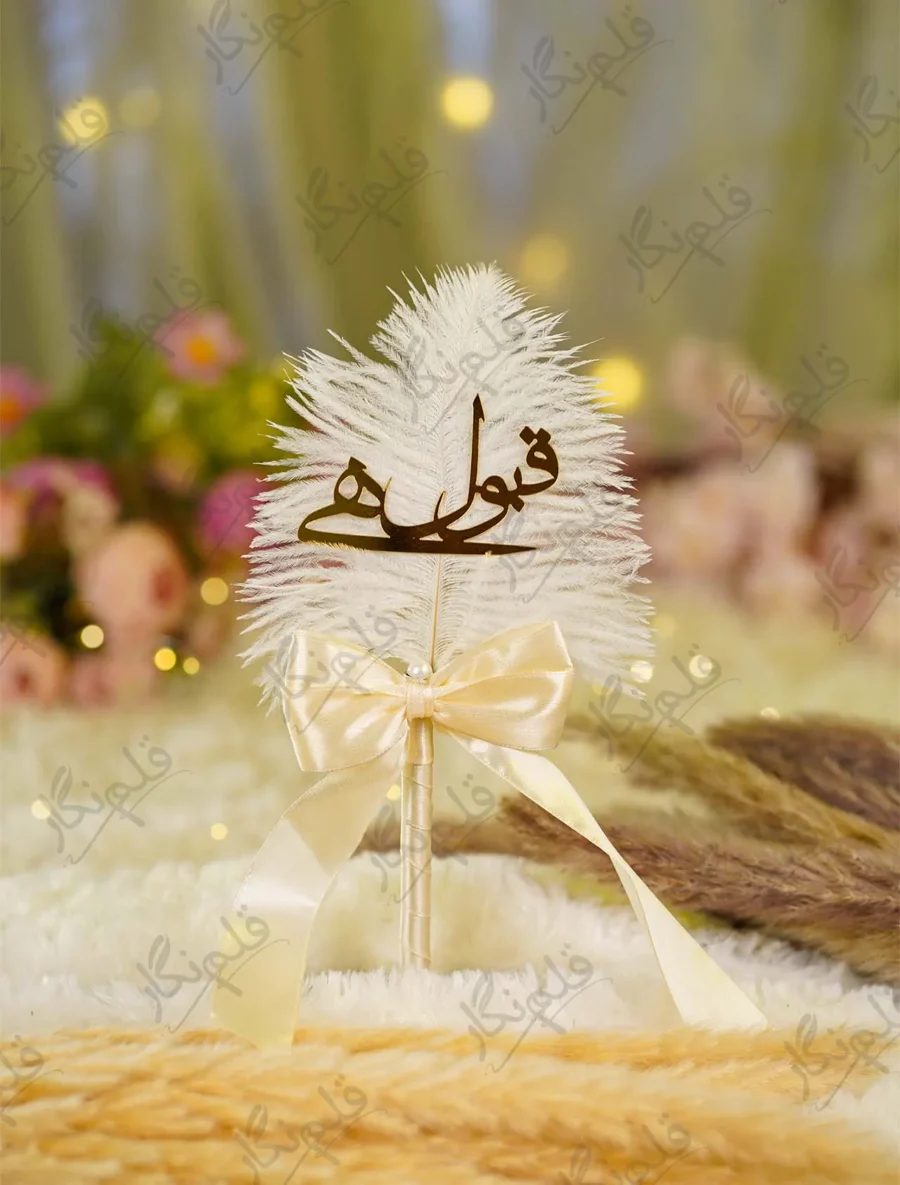 Elegant white feather Nikkah pen with gold Qabool Hai calligraphy against floral backdrop