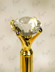 High angle close up of the multi faceted crystal glass diamond top on gold pen