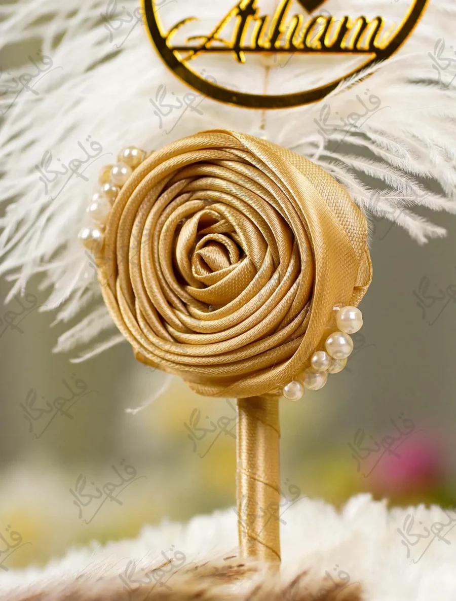 Close up of the handcrafted gold satin rolled rose and crescent pearl trim