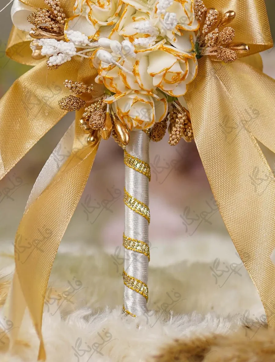 Detailed shot of the gold-brushed cream rose cluster and gold bow