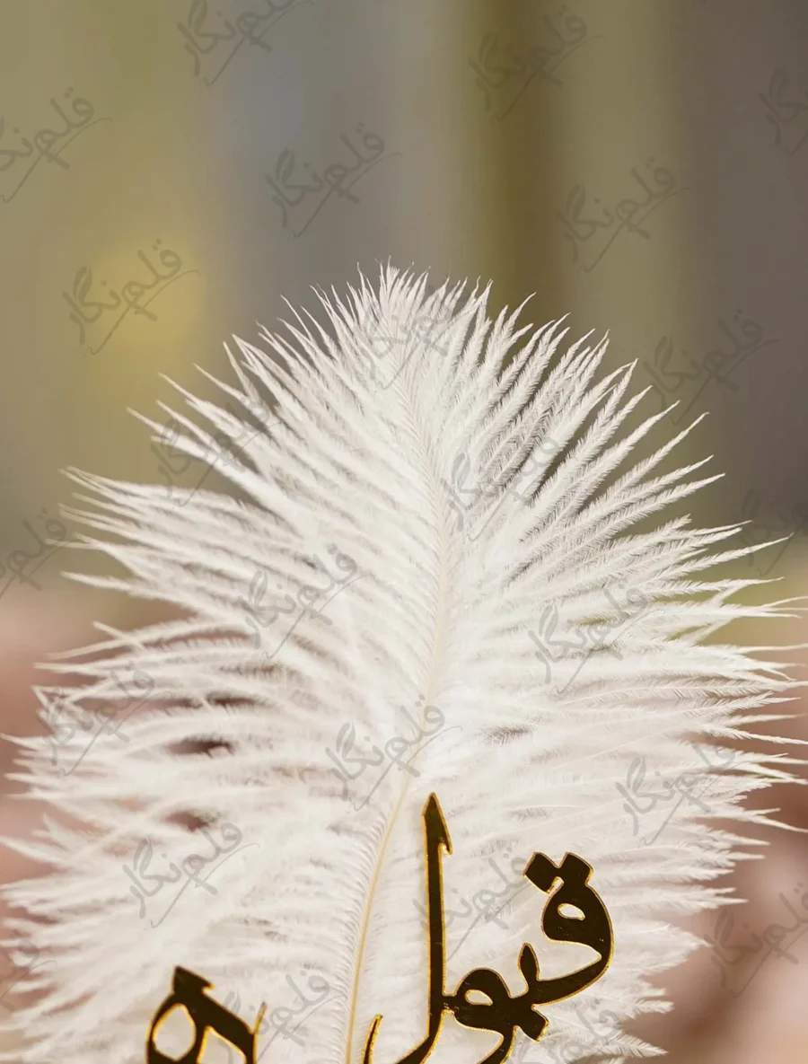 Close up of the golden mirror acrylic Qabool Hai calligraphy on the white feather