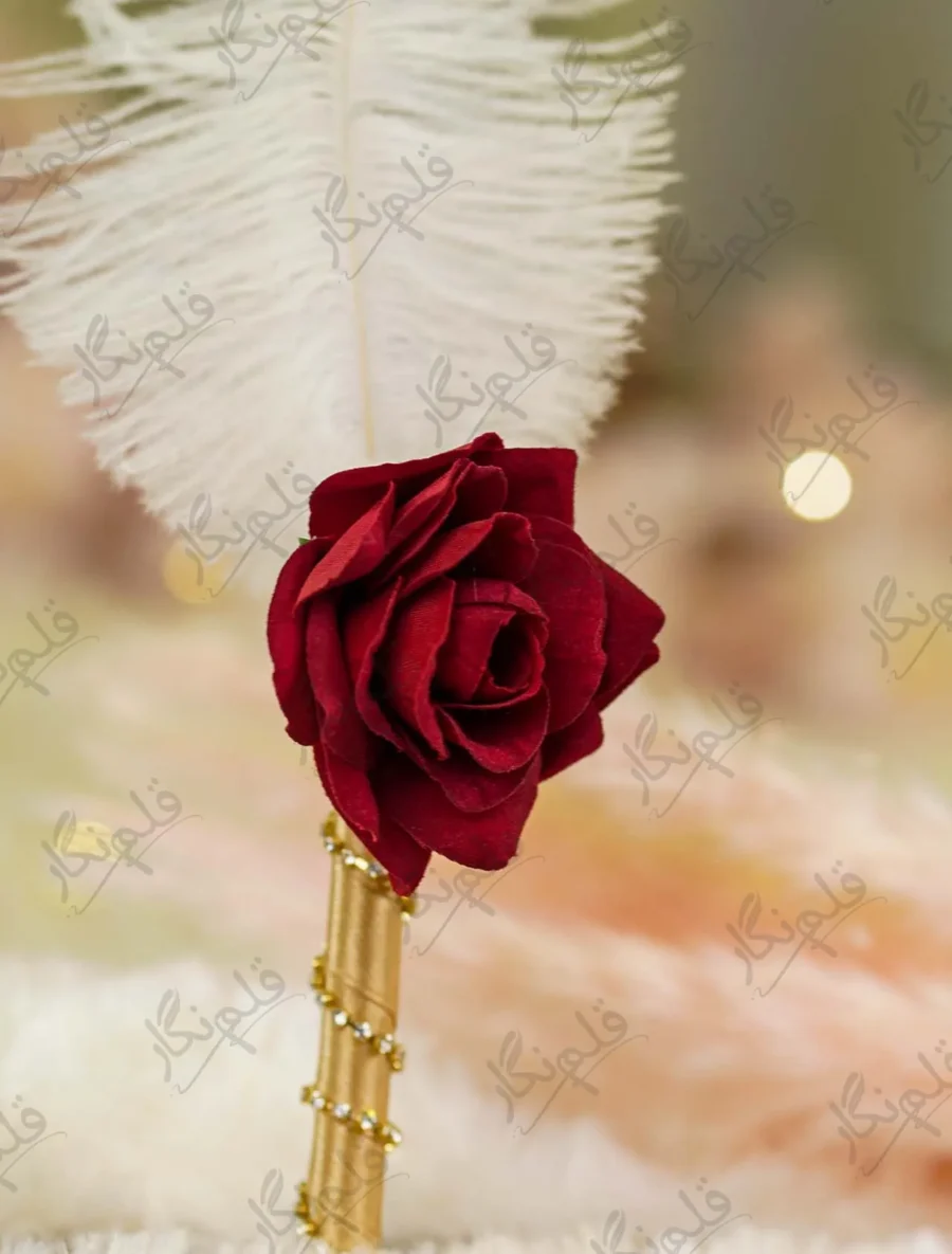 Close up of the red fabric rose at the base of the white feather on the signing pen