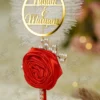 Close up of the couple name circle above the red rose on the white feather pen