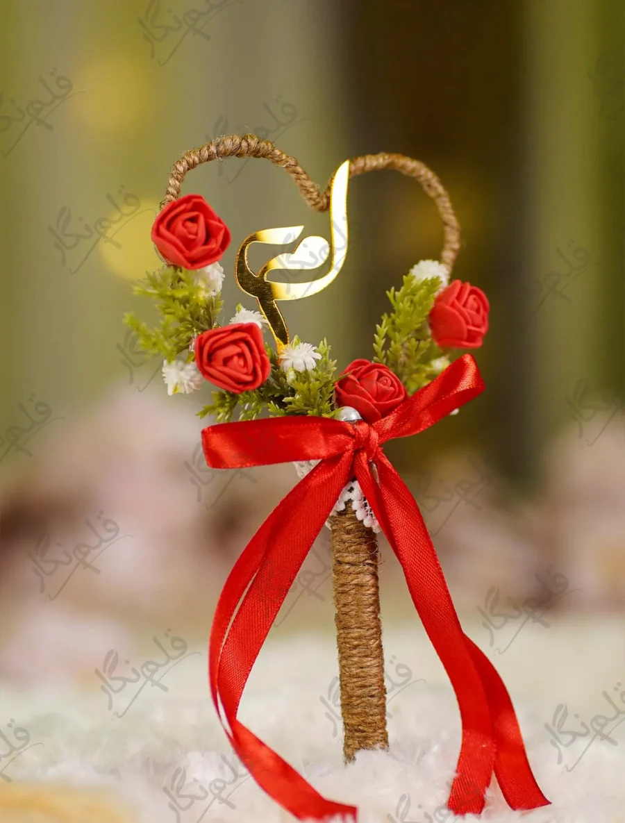 Side angle view of the red rose buds and green leaves on the wedding signing pen