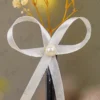 Close up of the white satin ribbon bow and central pearl bead accent