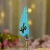 Detailed close up of the gold splatters on the teal quill feather