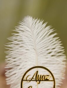 Close up of the golden mirror acrylic Qabool Hai calligraphy on the white feather