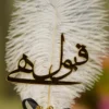Close up of the golden mirror acrylic Qabool Hai calligraphy on the white feather
