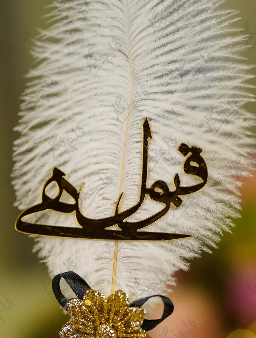 Close up of the golden mirror acrylic Qabool Hai calligraphy on the white feather